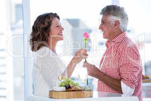 Mature man giving flower to happy woman