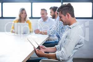 Businessman using digital tablet while colleagues in background