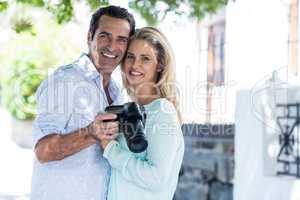 Happy couple with camera standing on street