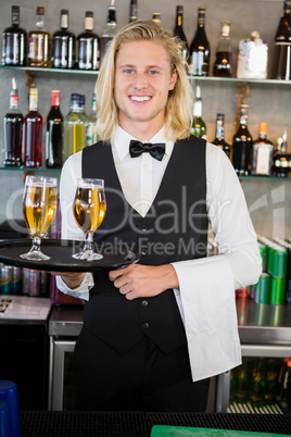 Portrait of waiter holding tray with glasses of beer