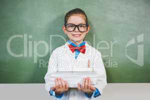 Portrait of smiling girl standing with a stack of books in class