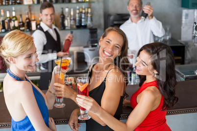 Happy female friends holding glass of cocktail at bar counter