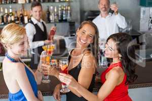Happy female friends holding glass of cocktail at bar counter