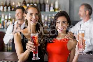 Two beautiful women holding cocktail glass