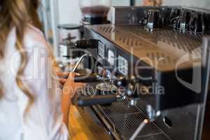 Mid section of waitress making cup of coffee