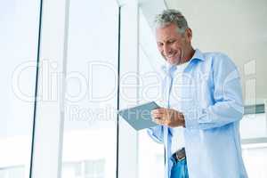 Low angle view of cheerful mature man holding tablet