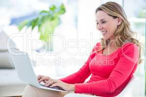 Woman smiling  while using laptop