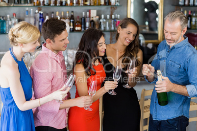 Friends looking man to open the champagne bottle