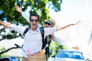 Couple with arms outstretched on bicycle