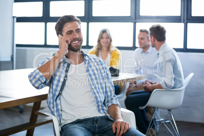 Creative businessman talking on cellphone by desk