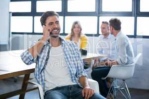 Creative businessman talking on cellphone by desk