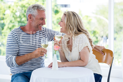 Smiling mature couple discussing while having wine