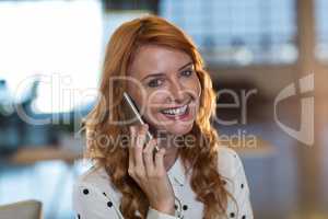 Portrait of smiling woman talking on phone in office