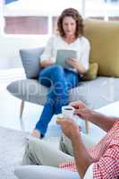 Midsection of man holding coffee cup at home with woman