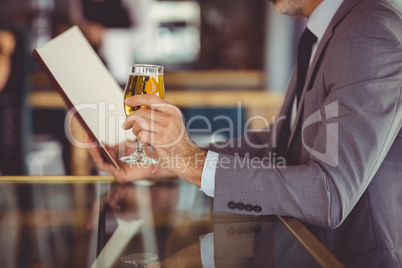 Businessman holding glass of beer and looking at menu