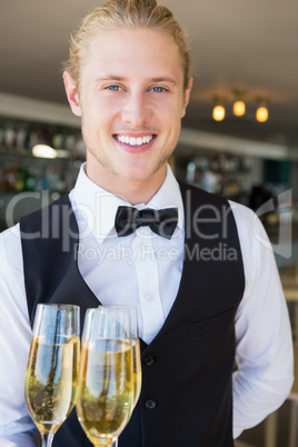 Portrait of waiter holding glasses of champagne