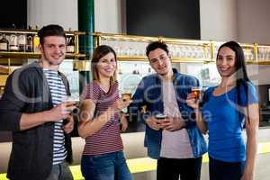 Friends smiling while holding beer glass at counter
