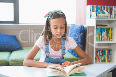 School girl reading a book in library