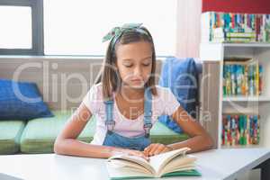 School girl reading a book in library