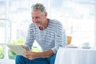 Smiling mature man using digital tablet