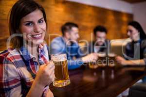 Woman holding beer mug while friends in background