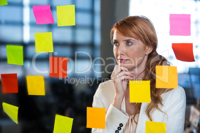 Thoughtful businesswoman looking at sticky notes