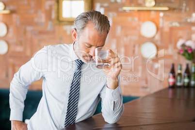 Businessman clutching whiskey glass to forehead