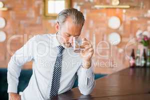 Businessman clutching whiskey glass to forehead