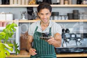 Portrait of waiter offering a cup of coffee