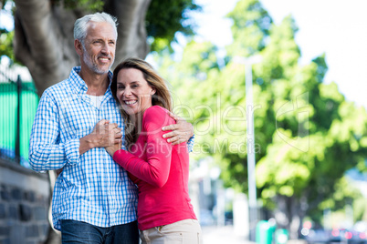 Smiling mature couple standing against tree