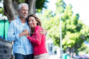 Smiling mature couple standing against tree