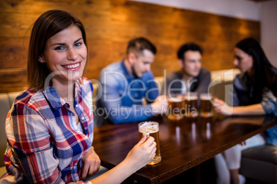 Woman holding beer mug with friends in background