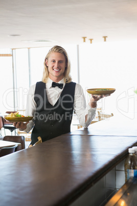 Waiter holding plated meals in restaurant