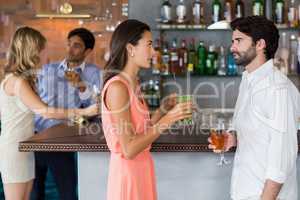 Couple holding a glass of cocktail in front of bar counter