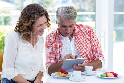 Couple looking in digital tablet at restaurant