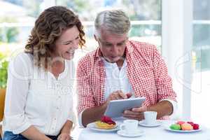 Couple looking in digital tablet at restaurant