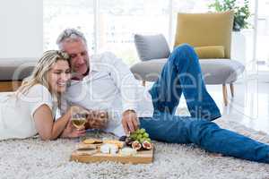 Smiling couple having food while lying on rug