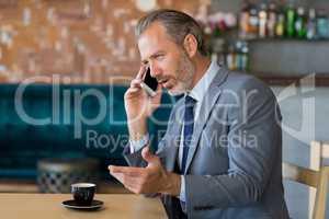 Businessman talking on mobile phone while having a cup of tea