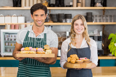 Portrait of waiter and waitress holding a tray of cupcakes