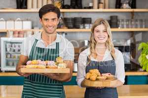 Portrait of waiter and waitress holding a tray of cupcakes