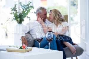 Romantic couple sitting on armchair with wine and gift box