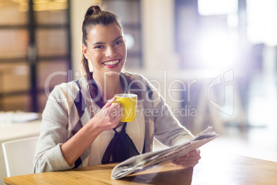 Portrait of smiling woman holding newspaper in office