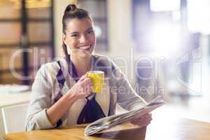 Portrait of smiling woman holding newspaper in office