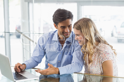 Happy couple using laptop in cafe