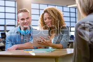 Colleagues smiling while looking in tablet computer