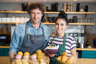 Waiter and waitress holding wooden tray and bowl with snacks and