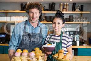 Waiter and waitress holding wooden tray and bowl with snacks and