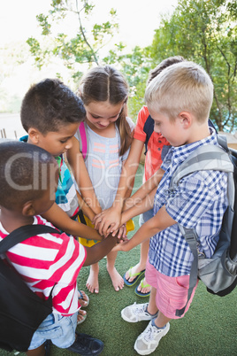 Schoolkids putting their hands together in campus