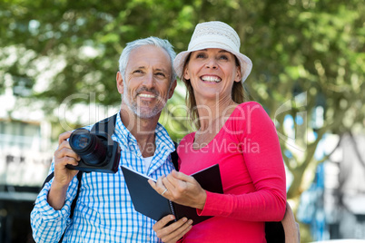 Couple looking away while standing against trees