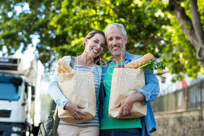 Couple holding shopping by tree